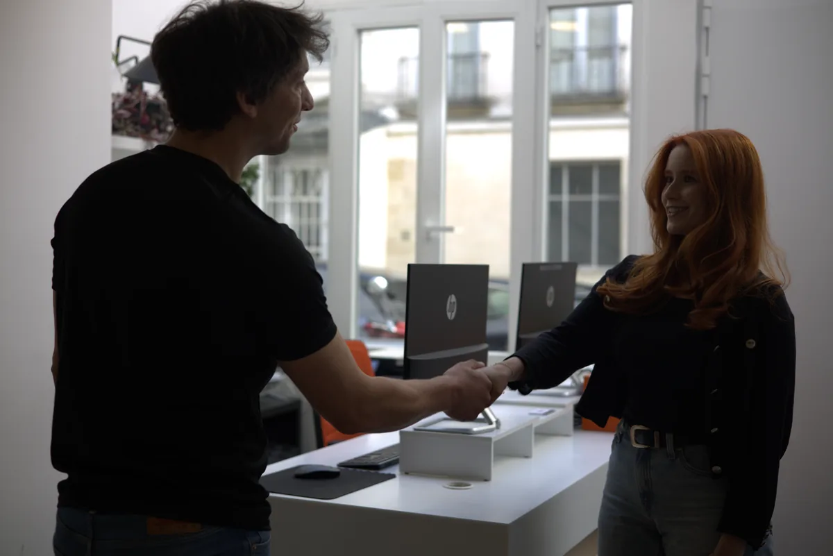 Welcome handshake between a team member and a visitor at the Marais front desk