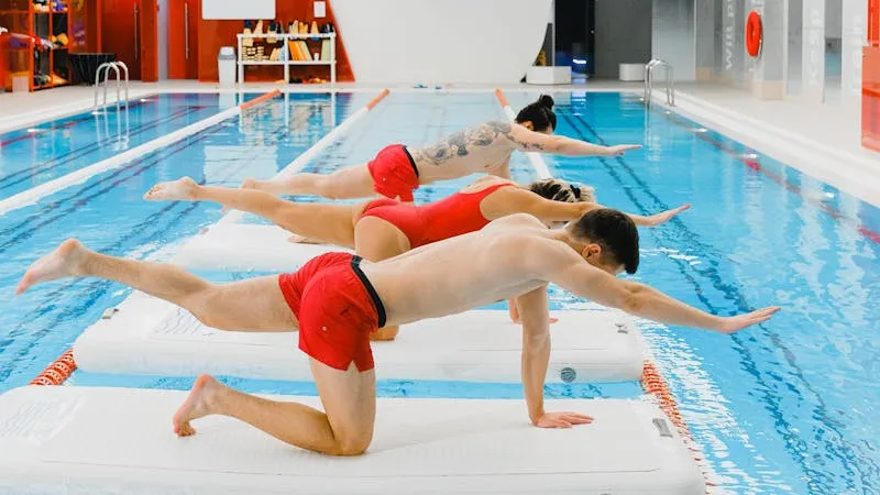 Groupe de patients realisant des exercices d'equilibre sur tapis flottants en piscine chauffee