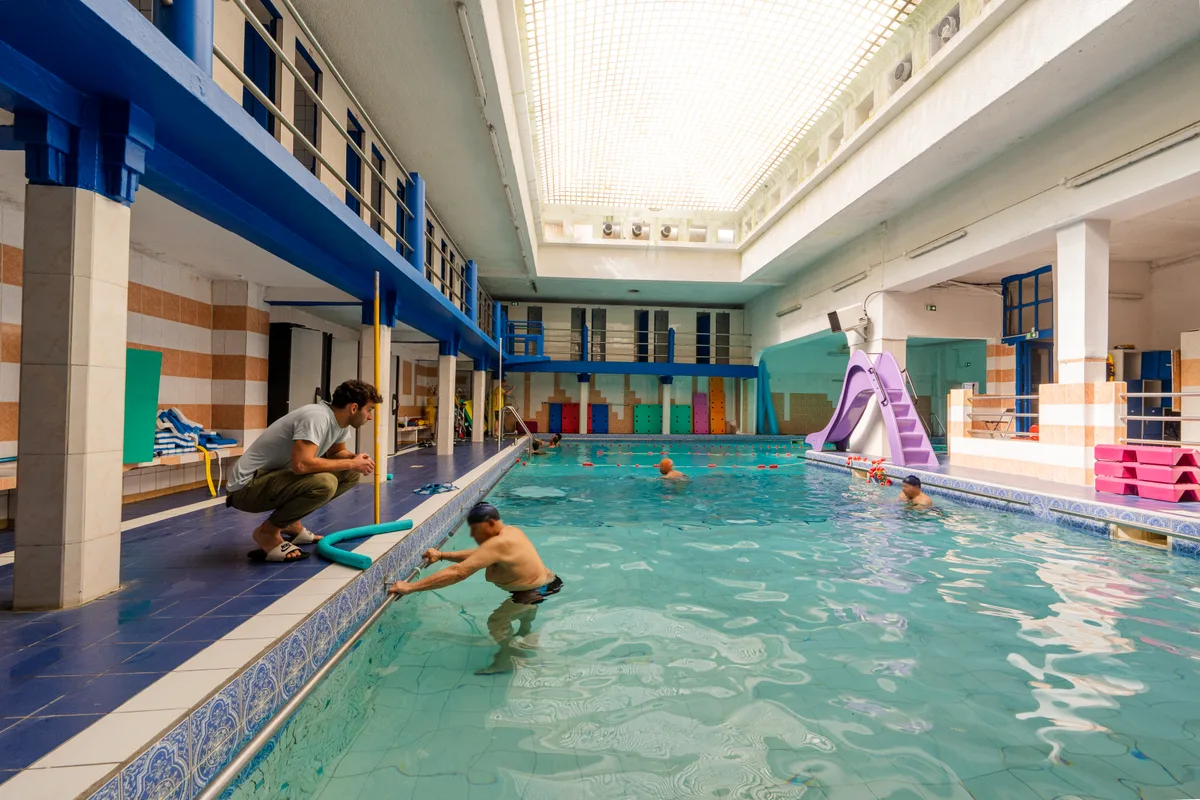 Patient réalisant un exercice appuyé à la barre dans le bassin de balnéothérapie d'Oberkampf