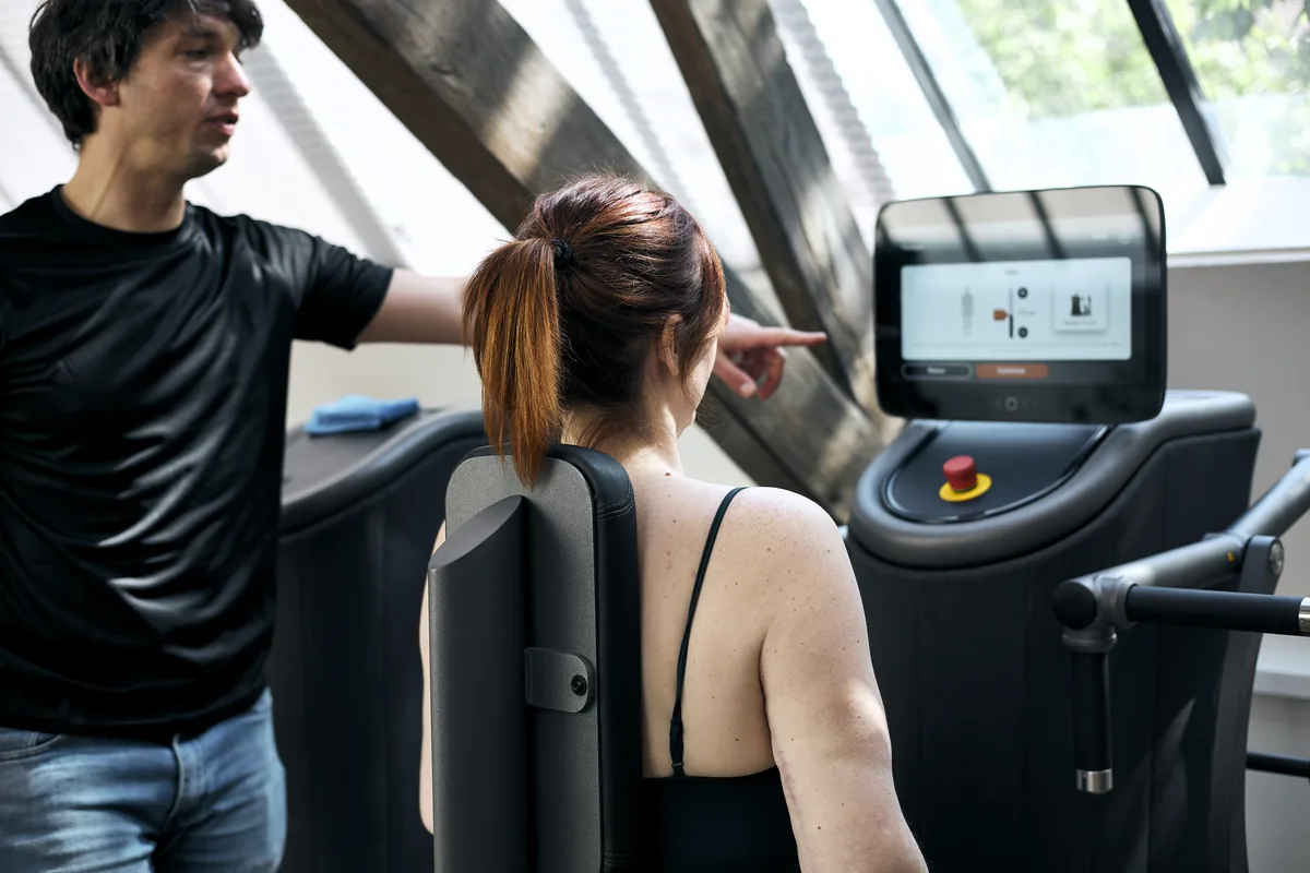 Physiotherapist showing the screen of an eGym training machine to a patient at the Marais clinic