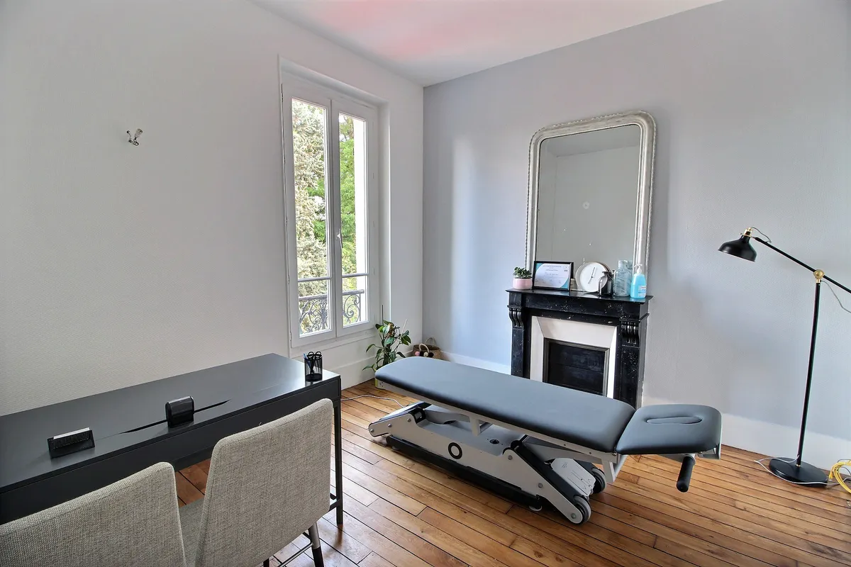 Treatment room at the Kinéau clinic with physiotherapy table, marble fireplace and wooden floor