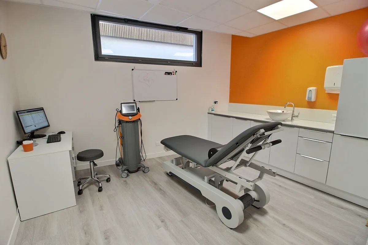 Salle de soins du cabinet KinéO2 avec table de rééducation et appareil d'ondes de choc