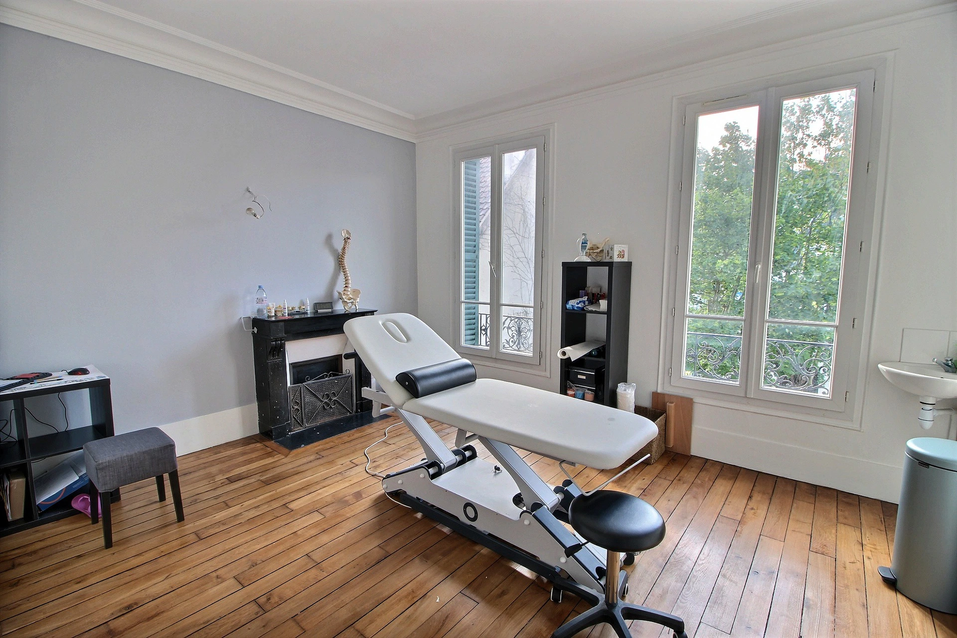 Salle de soins du cabinet Kinéau avec table de kinésithérapie électrique et colonne anatomique