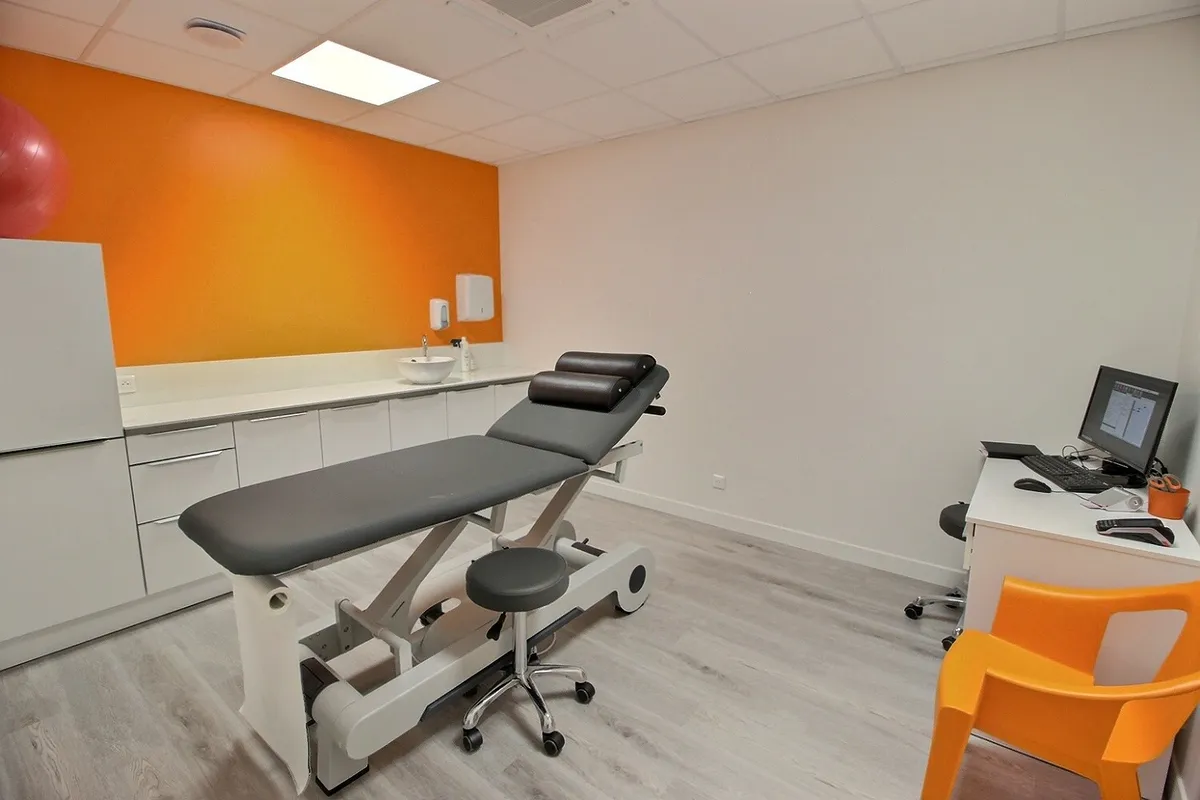 Salle de soins du cabinet KinéO2 au Perreux avec table de kinésithérapie électrique et mur orange